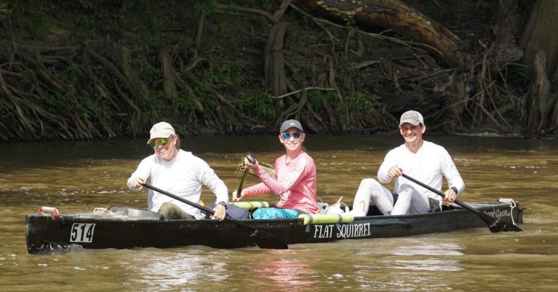 Three paddlers aboard the Flat Squirrel racing canoe, boat 514, during a Texas river race