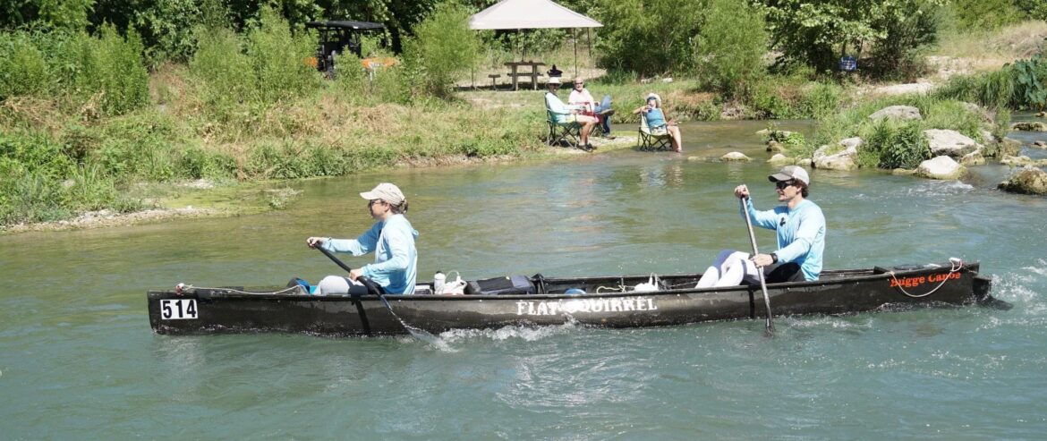 Spencer Fuller and wife racing the Flat Squirrel canoe past spectators on clear Texas water