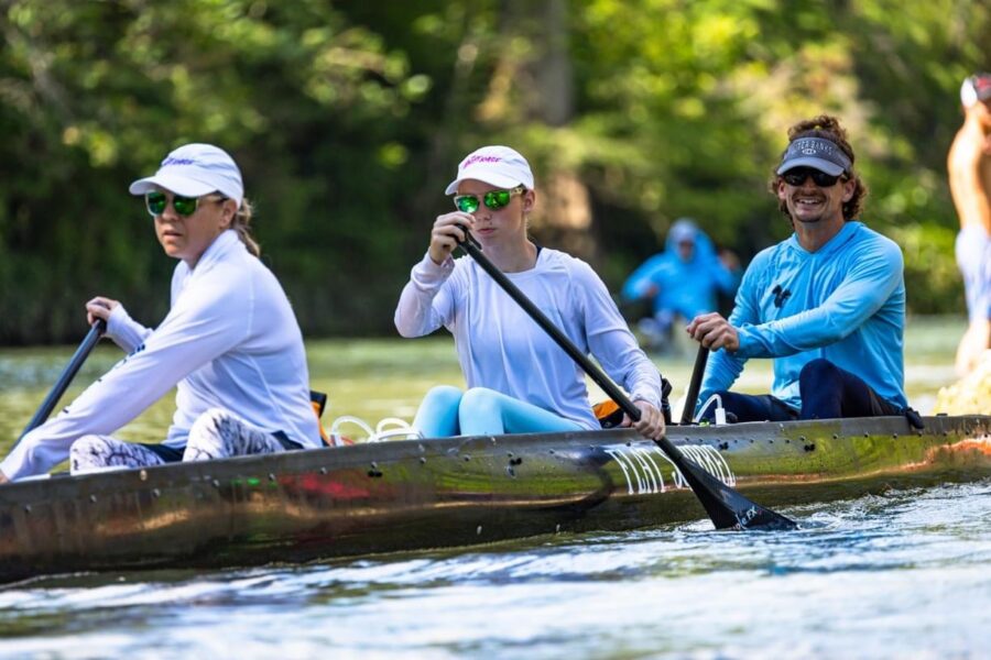 Team of three paddling a racing canoe together on a spring fed Texas river